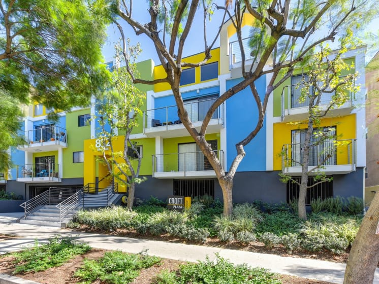 Blue/Yellow/Green  Apartment Exterior with View of Private Patio, Trees, Bushes
